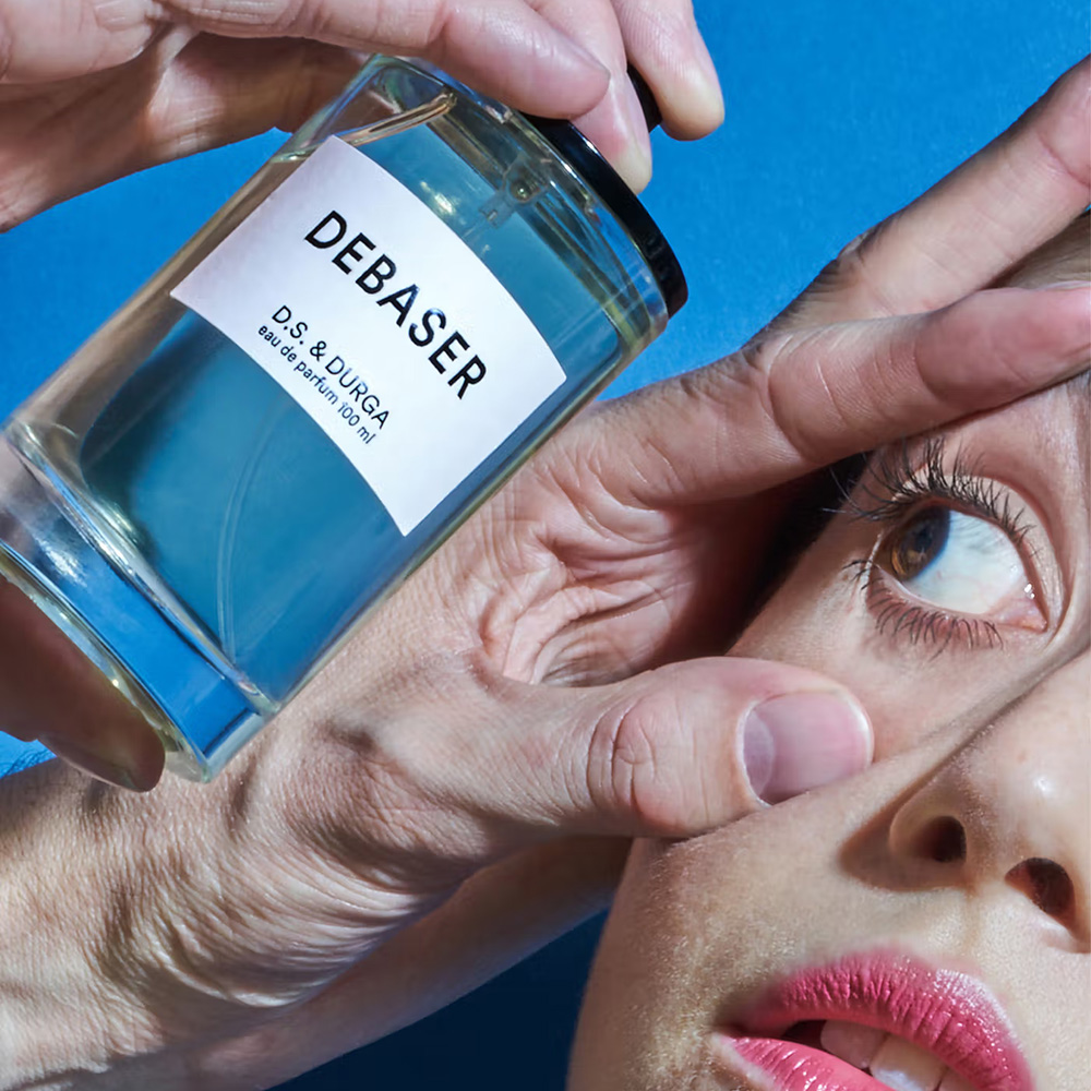 D.S. & Durga "Debaser" perfume bottle held near a woman's face